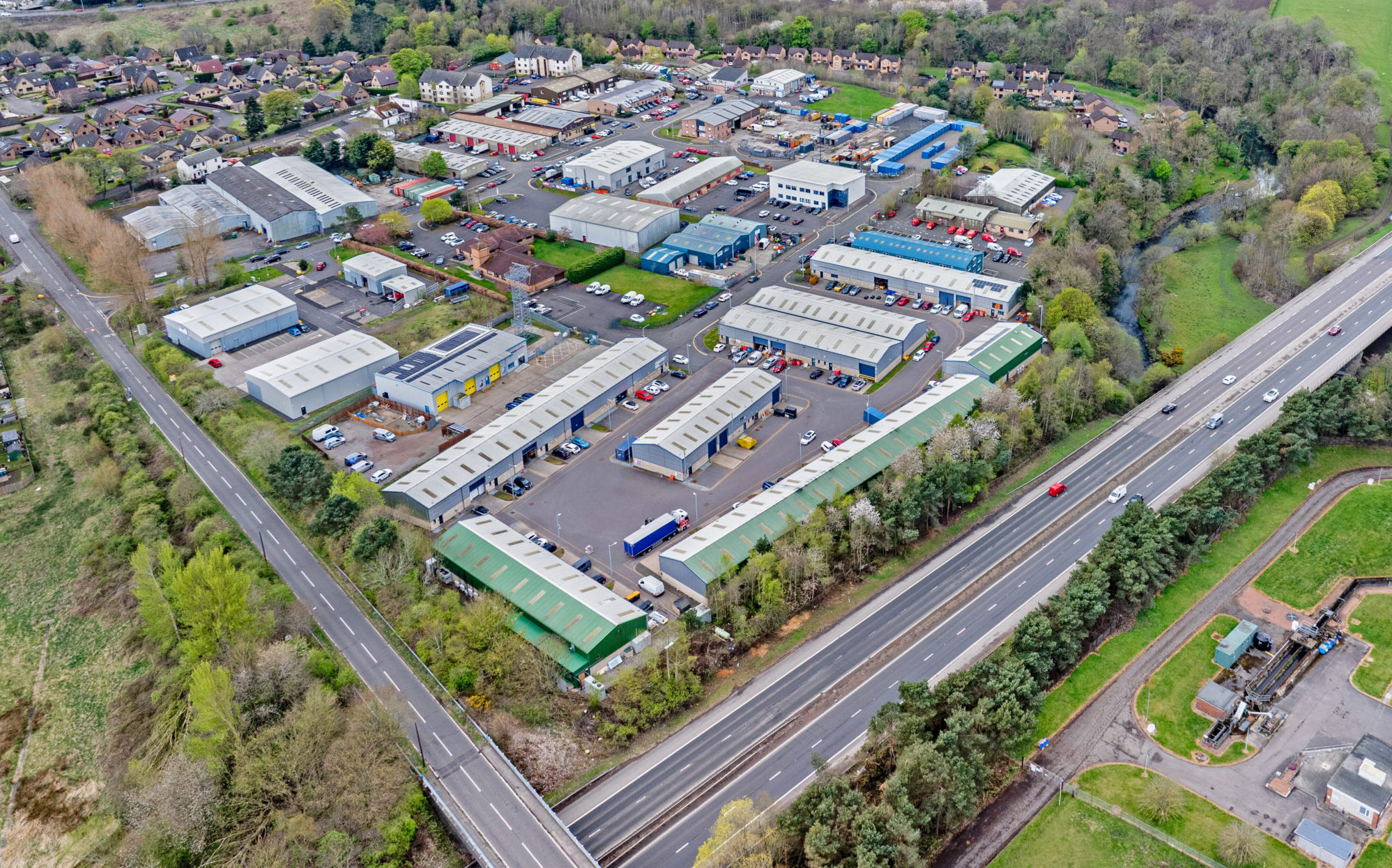 Drone photograph of Mill Road Industrial Estate in Linlithgow showing industrial units, Boxxs Self Storage containers, and nearby motorway access