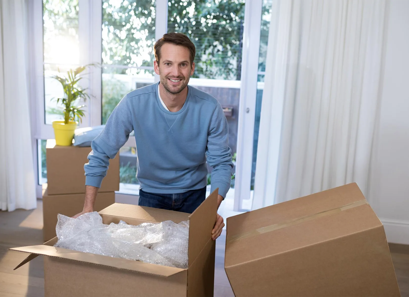 Person packing a moving box with protective bubble wrap using self storage packing tips to protect belongings